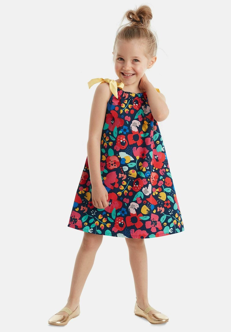 Vestido floral con un fondo azul marino y patrones vibrantes en rojo, amarillo y verde. Destacado con tirantes amarillos en los hombros y un corte a la altura de la rodilla.