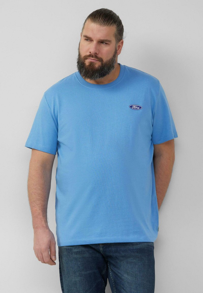 Lichtblauw katoenen t-shirt met een ronde halslijn, korte mouwen en een klein Ford-logo op de borst; gecombineerd met denim jeans.