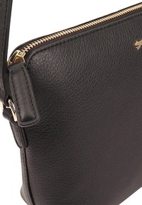 Zwarte leren schoudertas met een gestructureerde afwerking, gouden ritssluiting en een afneembare schouderband. Beschikt over een klein logo-detail aan de voorkant.