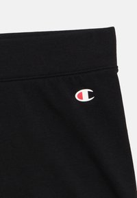 Μαύρο αθλητικό σορτς από απαλό ύφασμα, με μικρό λευκό και κόκκινο λογότυπο στη μέση και μαλακό ελαστικό τελείωμα.