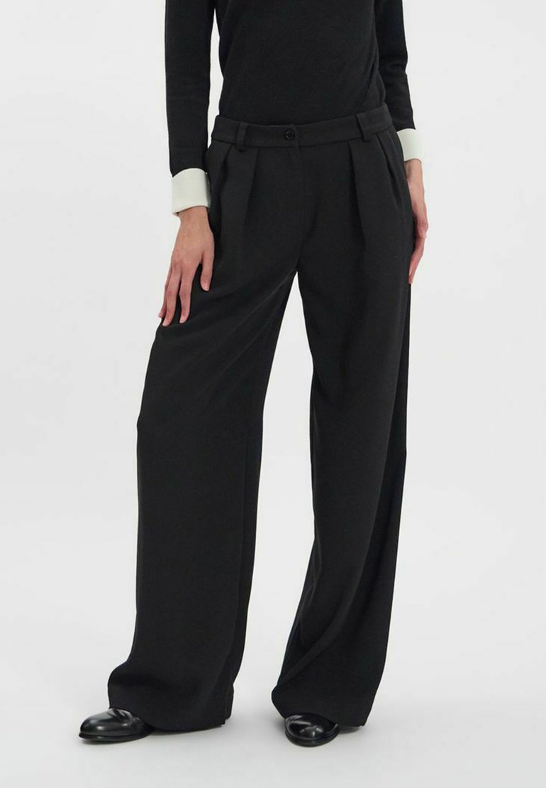 Pantalons noirs à jambe large avec plis à l'avant, fabriqués en tissu lisse, dotés d'une taille ajustée et d'une fermeture à un bouton.