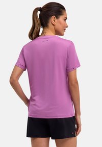 Koszulka sportowa z krótkim rękawem, dopasowana, w jasnopurpurowym kolorze, wykonana z teksturowanej tkaniny, z małym logo na górnej części pleców.