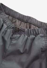 Shorts grișci închis, cu un băgare elastică și un șnur de ajustare, realizate dintr-un material neted și ușor; cusături minime și fără modele vizibile.