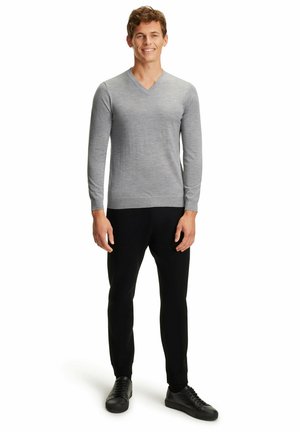 Pull en V à manches longues gris en tissu doux, associé à un pantalon noir ajusté et des baskets noires ; design simple et moderne.