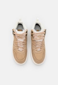 Zapatillas beige texturizadas con acentos en crema, cuello acolchado, cordones melocotón y detalle de logo. Presentan una suela resistente y una tira de agarre en el talón.