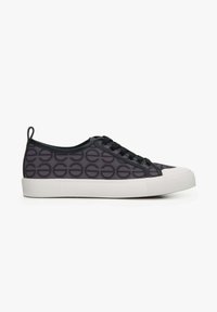 Zwarte sneakers met een patroon van cirkels, rubberen zool, ronde neus en zwarte veters. Voorzien van een trekband aan de achterkant en textuurpanelen aan de zijkanten.