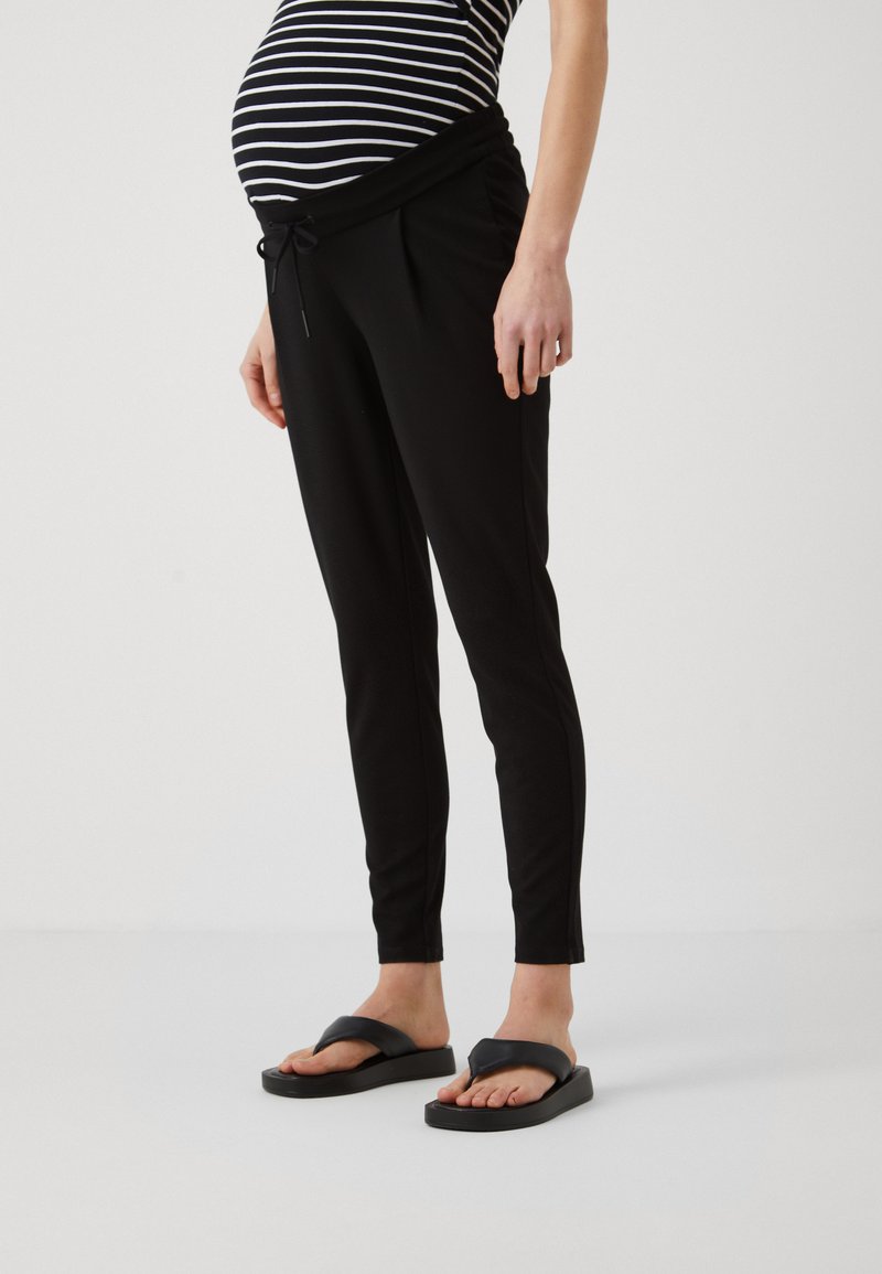 Black maternity joggers featuring a drawstring waistband, tapered legs, and soft fabric. Paired with flat black flip-flops.