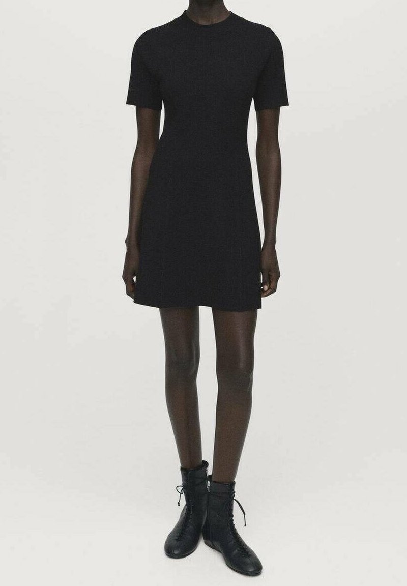 Robe noire à manches courtes avec un col rond, une coupe ajustée, un tissu texturé et une finition lisse, associée à des bottines noires à lacets.