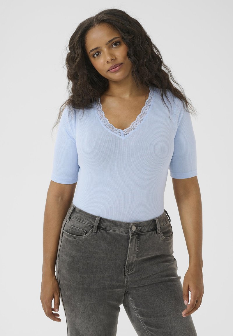 Haut bleu clair côtelé avec un décolleté en V profond et une bordure en dentelle, associé à un pantalon en denim gris, présentant une coupe décontractée et des détails texturés subtils.