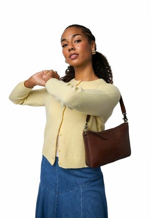 Hnědá kožená kabelka na zip, nošená na ramenním popruhu. Modelka má na sobě světle žlutý cardigan a džínovou sukni.