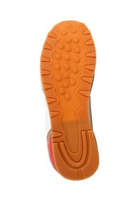 Suela de zapato en goma naranja con patrones de tracción circulares, rodeada por una parte superior blanca y acentos rojos. Texturizada para ofrecer tracción y durabilidad.