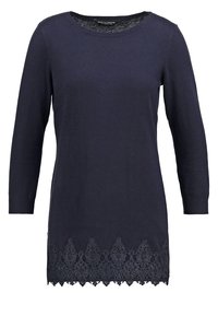 Mörkblå långärmad tröja med rundad halsringning och intrikat svart spetsdetalj vid fållen. Slät stickad tyg med en något lös passform.