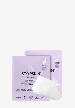 Deux sachets de masque exfoliant pour les pieds STARSKIN couleur lavande à côté d’un masque jetable blanc en forme de chaussette.
