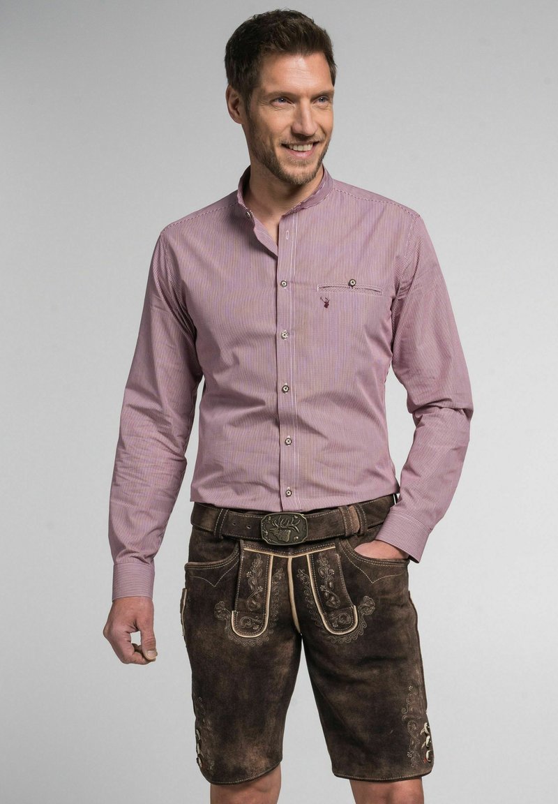 Rood en wit gestreepte overhemd met knopen en een zak, gecombineerd met bruine leren lederhosen met decoratieve stiksels en een riem.