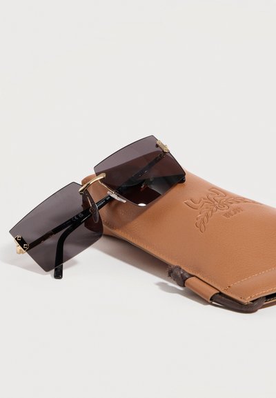 Ορθογώνια γυαλιά ηλίου με σκουρόχρωμους φακούς και χρυσές λεπτομέρειες, τοποθετημένα πάνω σε θήκη από καφέ δέρμα με ανάγλυφο διακοσμητικό λογότυπο.