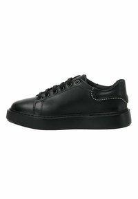 Zapatilla de cuero negra con puntera redonda, diseño de cordones, suela texturizada y tachuelas decorativas a lo largo del tacón. Acabado suave en general.