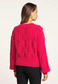 Pulover tricotat fucsia cu un model texturat în diamant, mâneci supradimensionate și accente cu perle pe umăr. Bordură și manșete ribbate.
