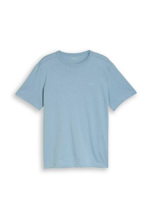 Jasnoniebieska koszulka z krótkim rękawem i okrągłym dekoltem, z subtelnym logo na lewej piersi, rozłożona na płasko na białym tle.