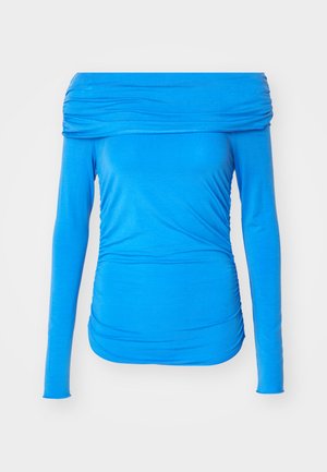 Zila off-the-shoulder garā piedurkņu blūze, izgatavota no elastīga auduma, ar drapējuma detaļām sānos, lai radītu pieguļošu izskatu.