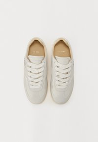Sneaker grigio chiaro realizzati in suede e pelle, con lace bianchi piatti, punta tondeggiante e un logo discreto sui lati.