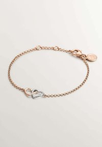 Pulsera de metal en oro rosa con un diseño de cadena retorcida, que presenta un charm en forma de corazón entrelazado de plata y un cierre de langosta con un pequeño colgante.