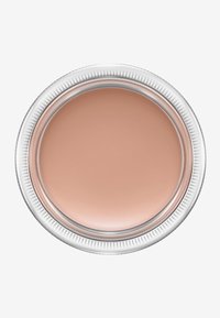 Corrector cremoso beige en una lata redonda de plata con bordes acanalados. Textura suave y superficie reflectante que destaca su consistencia cremosa.