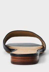 Fekete bőr szandál nyitott hátsó résszel, sima felső résszel és fából készült sarokkal. Lapos talp, ívelt talpággyal.