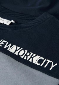 Felpa blu navy con sezione inferiore grigia e grande testo "NEW YORK CITY" in bianco sulla parte superiore. Materiale morbido in misto cotone.