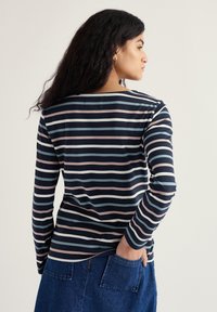 Tengerészkék hosszúujjú póló, világos rózsaszín és világoskék vízszintes csíkokkal. Puha, könnyű anyagból készült, kerek nyakkivágással és laza illeszkedéssel.