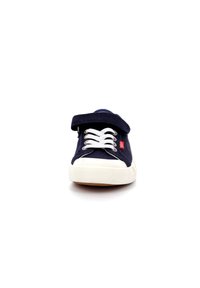 Zapatillas de lona azul marino con acentos blancos, con cinta de velcro y cordones, punta redondeada y suela de goma.