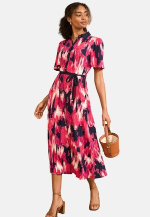 Abito midi a fantasia floreale in rosa e blu navy con maniche corte, chiusura a bottoni e cintura coordinata. Un modello tiene una borsa rotonda marrone.