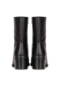 Botas de tobillo de cuero negro con un acabado suave, puntera redondeada y tacón grueso. Presentan líneas limpias y costuras mínimas.