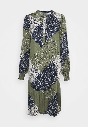 Langärmliges Kleid mit Patchwork-Design in Grün, Marineblau und Weiß mit floralen und tierischen Mustern. Knopfleiste am Ausschnitt.
