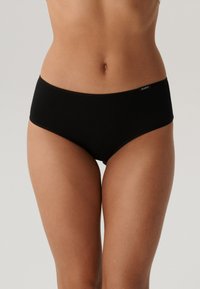 Czarne bawełniane slipy o gładkiej fakturze i prostym designie. W pasie znajduje się mała metka z boku. Klasyczny krój hipster.