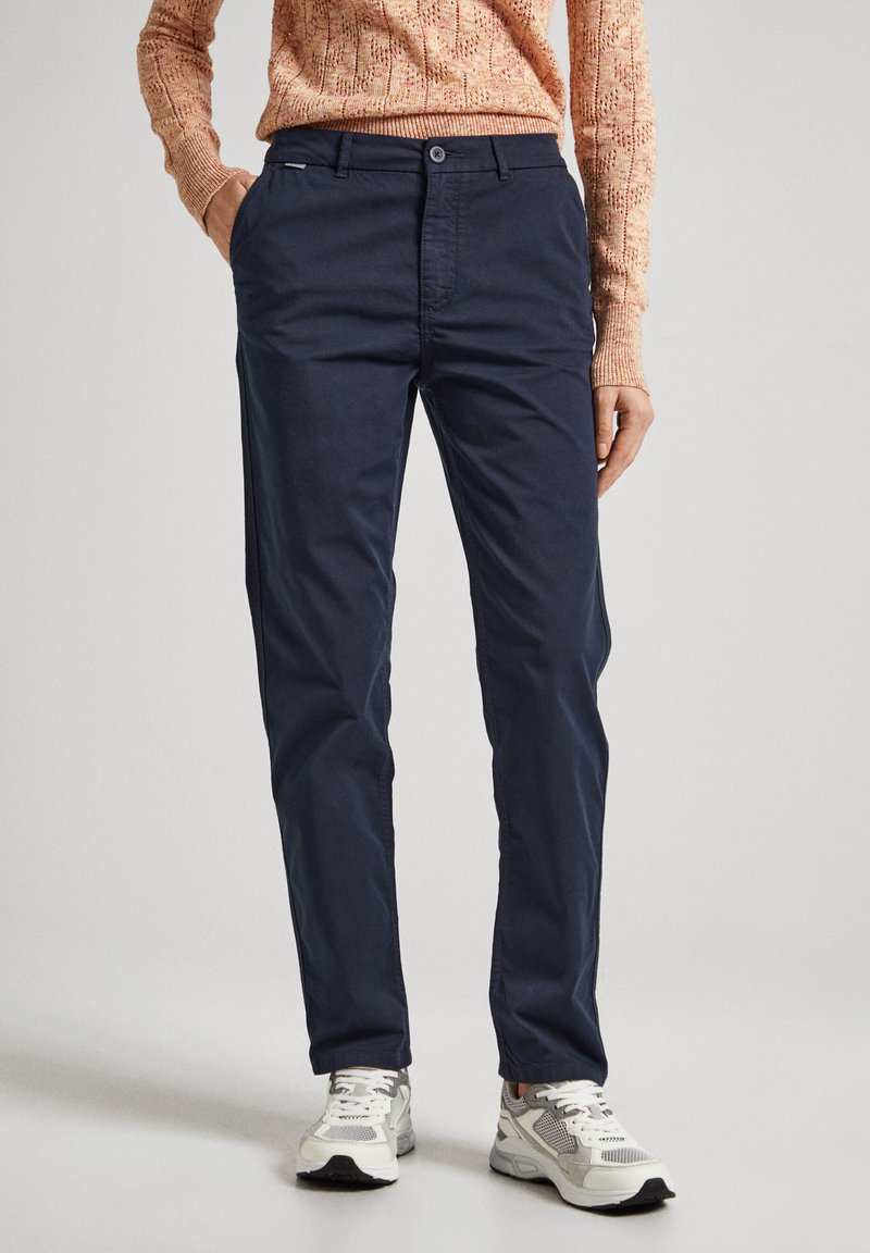 Marineblå chinos laget av lett stoff, med rett snitt, knappelukking og sidelommer. Kombinert med grå sneakers.
