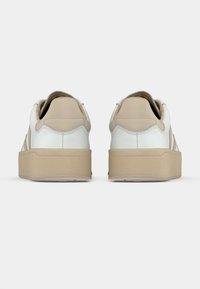 Λευκά και μπεζ αθλητικά παπούτσια με λείο δερμάτινο επάνω μέρος, στρογγυλεμένη μύτη και χοντρή πλατφόρμα μπεζ σόλας. Διαθέτουν διακριτικές λεπτομέρειες ραφής.