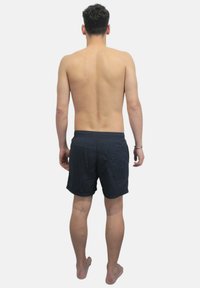 Bañador masculino de color azul oscuro, fabricado en un material ligero; cuenta con una cinturilla con cordón y bolsillos laterales. Se muestra desde la parte posterior.