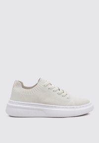 Zapatillas de punto blancas con una parte superior texturizada, cuello elástico y suela de goma. Presentan un sutil logotipo en el costado y en los cordones.