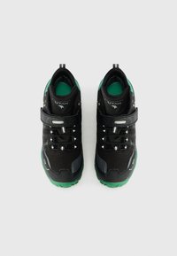 Tênis atléticos com marca de Utah, nas cores preto e verde, com fechos de gancho e laço e atacadores elásticos, exibidos lado a lado sobre um fundo branco.