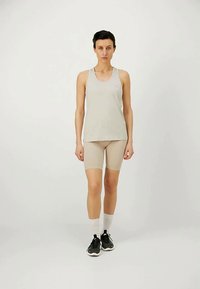Lys grå tank topp og beige sykkelshorts, laget av stretchy stoff, båret med sorte joggesko og hvite ankelstrømper. Enkelt, tettsittende design.