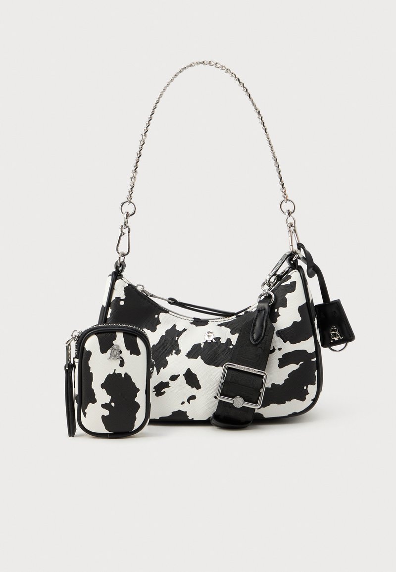 Bolso de mano con estampado de vaca en blanco y negro, con una cadena plateada, que cuenta con un mini bolso extraíble y un exterior liso y texturizado.