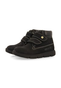 Bottines en velours noir avec des sangles Velcro, semelles en caoutchouc, couture contrastante et bout rond. Présente un texte en relief sur le côté.