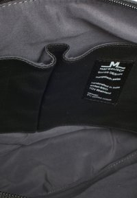 Interno di una borsa di tessuto nera con una foderatura grigia liscia, dotato di più tasche e di un'etichetta. Il materiale sembra resistente e ben cucito.