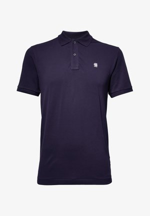 Polo de color azul marino hecho de algodón, con un collar clásico, tapeta de tres botones, mangas cortas y un pequeño logo en el pecho.