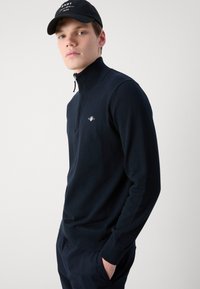 Navy zip-neck sweater made of knit fabric, featuring a relaxed fit, ribbed cuffs, and a small logo on the chest. Lightweight design.