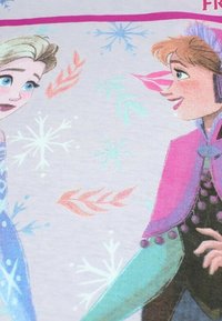 T-shirt avec des illustrations colorées de deux personnages féminins aux cheveux clairs et foncés, entourés de flocons de neige et de motifs floraux sur un fond clair.