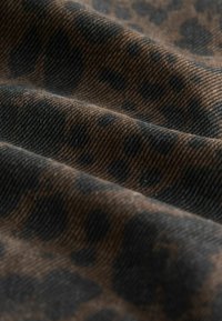Leopardprint stof in tinten van bruin en zwart, met een gestructureerd oppervlak en zichtbare plooien, wat een gevoel van diepte oproept.