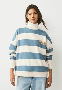 Striped sweatshirt in blue and cream, featuring a high neck and ribbed cuffs. Includes "Colorado est 1972" embroidered detail.