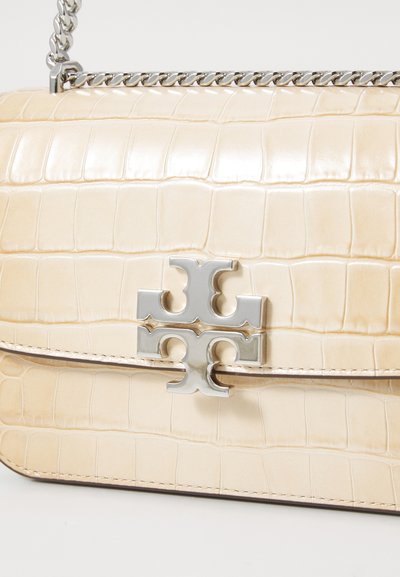 Beige faux crocodile leather handbag with a silver chain strap and a prominent silver logo accent on the front flap.