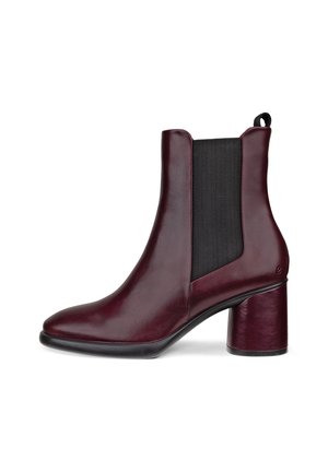 Stivaletto in pelle bordeaux con un pannello elastico nero spesso e un tacco geometrico. Texture liscia con una punta appuntita.
